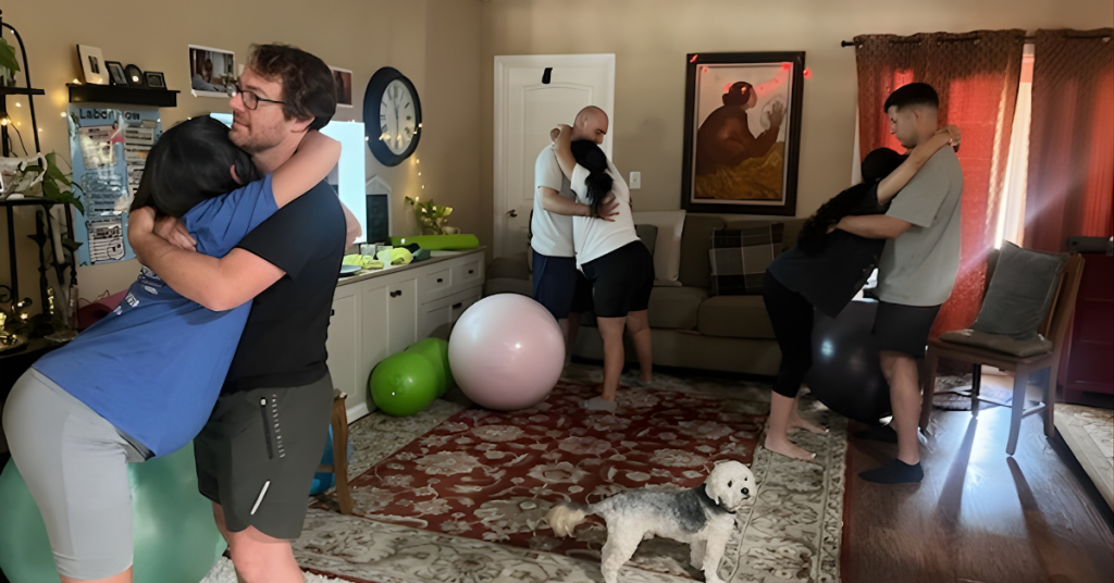Couples practicing partner support techniques during Lamaze childbirth classes in Los Angeles, using movement and positioning to prepare for labor in a cozy home setting.