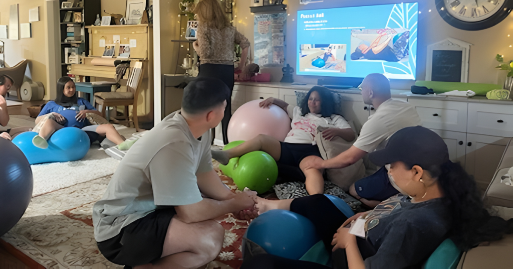 Small group Lamaze childbirth class with expectant parents using birth balls and learning comfort techniques for labor in an in-person prenatal class in Los Angeles.