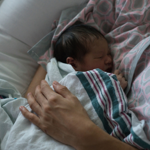 mom holding newborn in hospital bed after giving birth